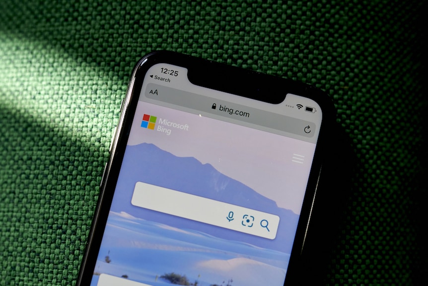Телефон на зеленому тлі, що показує домашню сторінку Bing.